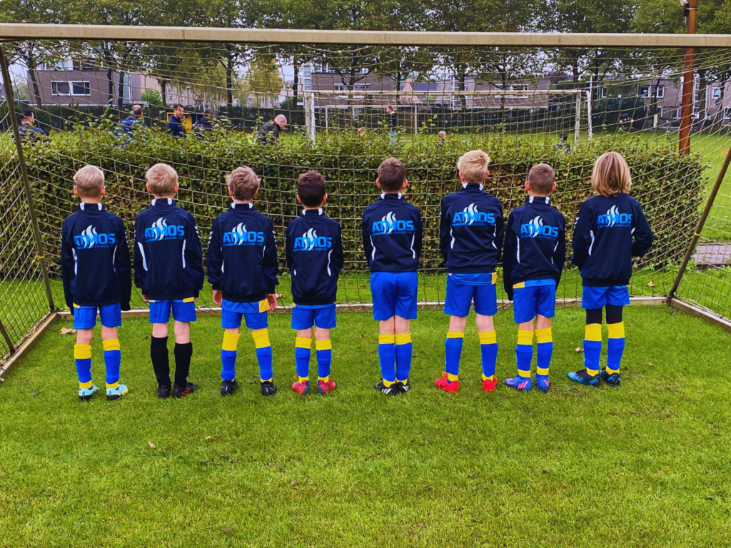 Op het voetbalveld staat een team in tenue met het logo van atmos engineering achterop